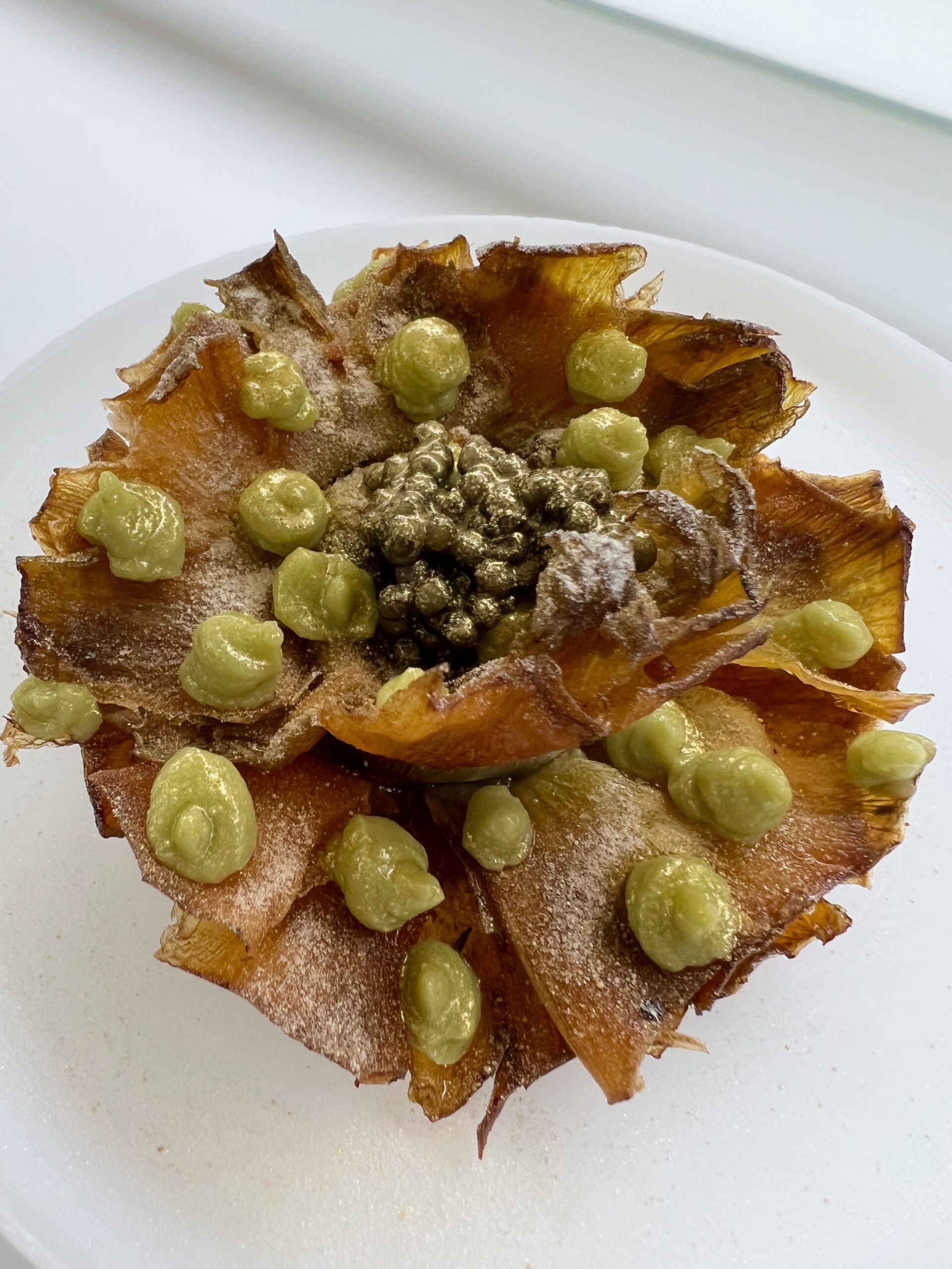 Fried Artichoke Flower topped with avocado sauce, caviar, gold powdered sugar 